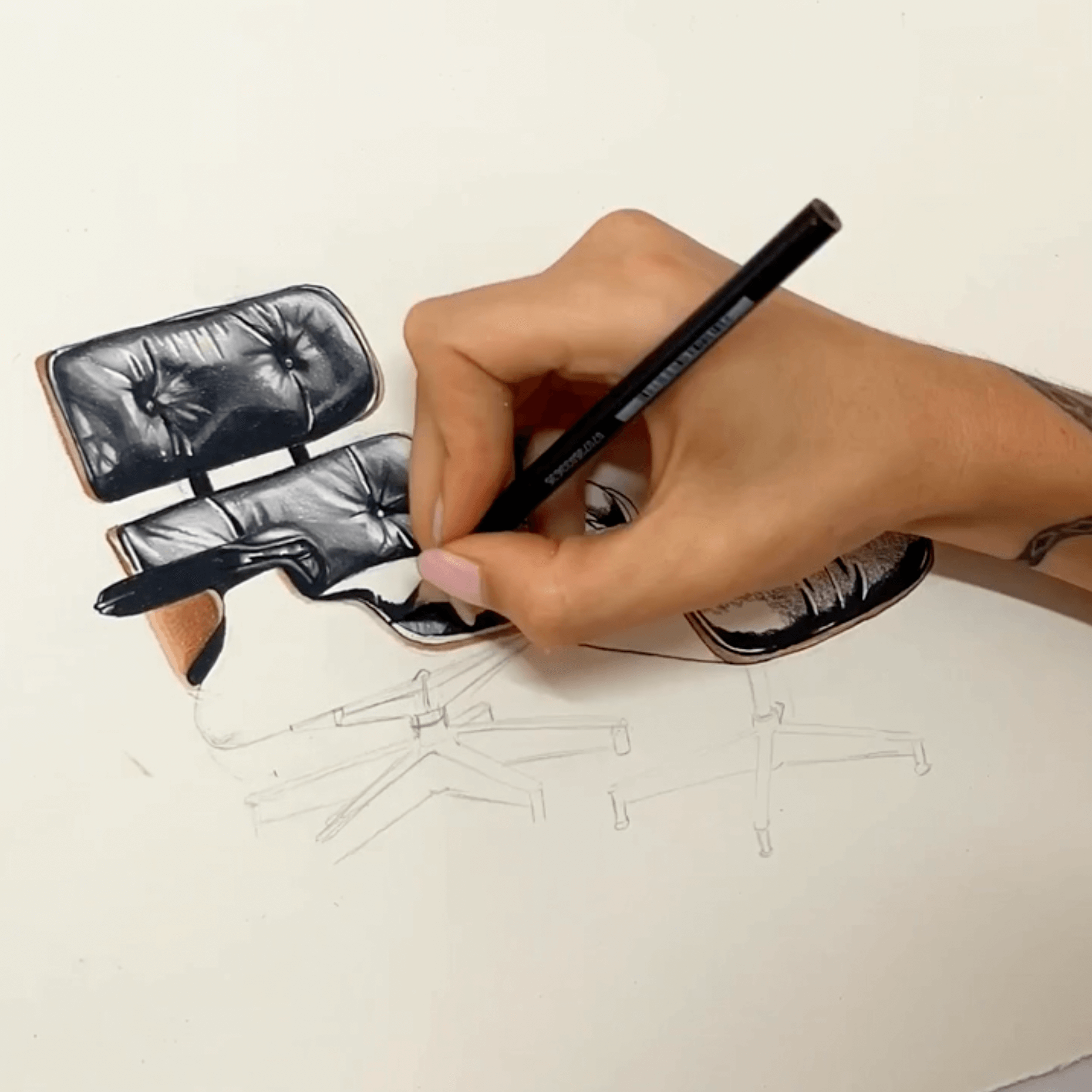 Woman's hand holding a pencil drawing an Eames Lounge Chair in a timelapse.